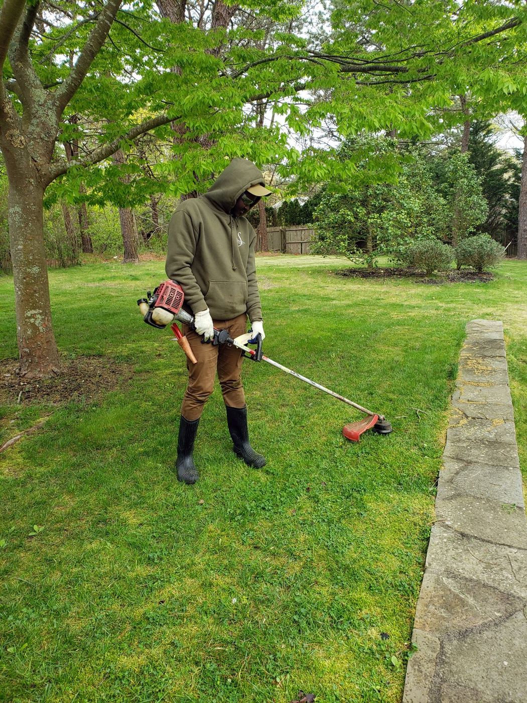 Gardener trimming a lawn edge with a brush cutter